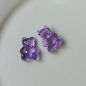 Macro detail of two purple transparent resin gummy bear charms on a white ceramic plate