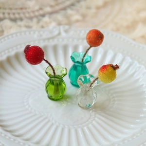 Close-up of miniature ribbed glass vases in green, blue, and clear with frosted berry sprigs