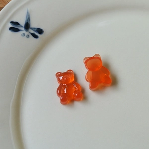 Detailed close-up of translucent orange gummy bear resin charms on a porcelain plate
