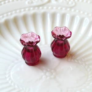 Macro shot of two miniature fuchsia glass vases with fluted texture and wavy rims