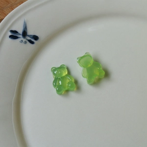 Close-up of translucent lime green resin gummy bear charms on a decorative white porcelain plate