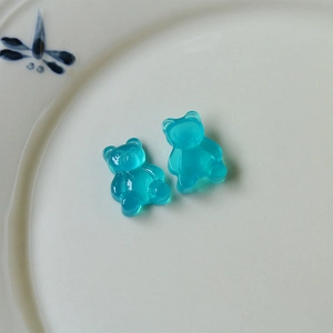Detailed macro view of two translucent blue resin gummy bear charms on a ceramic plate