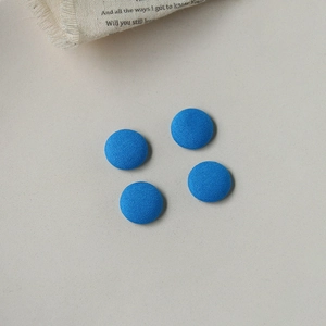Nahaufnahme von vier leuchtend blauen Stoffknöpfen für DIY-Näharbeiten auf hellem Hintergrund