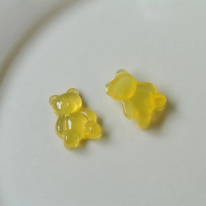 Macro shot of two yellow translucent resin gummy bear charms on a white ceramic plate