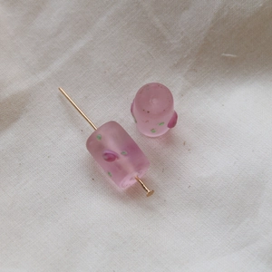 Macro detail of cylindrical pink frosted glass beads with floral accents for DIY jewelry
