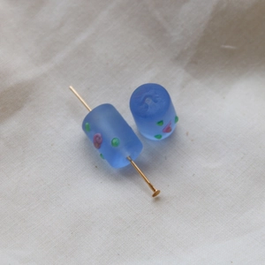 Close-up of frosted blue glass cylinder beads with floral patterns for DIY jewelry