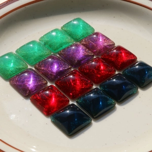 Macro shot of colorful resin cabochons with gold fiber textures in 4x4 grid
