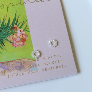 Close-up of elegant small wreath-shaped earrings made of polished white faux pearls