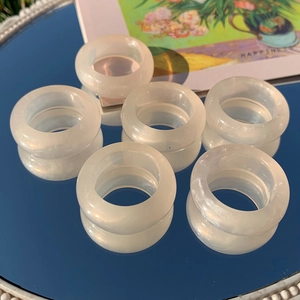Detailed view of six milky white resin rings arranged on a blue reflective surface