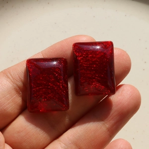 Close-up of red rectangular resin charms with golden fiber texture for DIY jewelry making