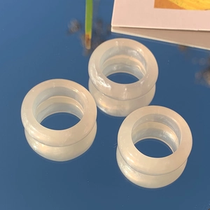 Three trendy milky white resin rings with a minimalist smooth finish on a blue mirror