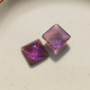 Close-up of translucent purple square resin charms with internal gold wire fibers