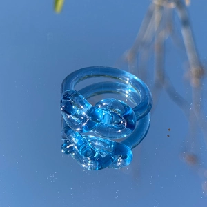 Makro-Detail eines lichtdurchlässigen blauen Harzknotenrings mit eleganter Spiegelung