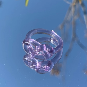 Makroaufnahme eines violetten Harzknotenrings mit lichtdurchlässigem Finish auf einem Spiegel