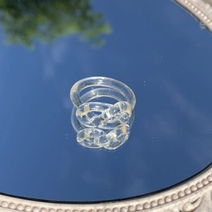 Nahaufnahme eines klaren Harzrings mit Knotendesign, der den blauen Himmel reflektiert