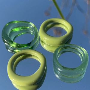 Dettaglio di quattro anelli irregolari in resina verde matcha con finitura lucida