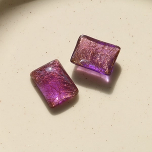 Macro detail of two purple translucent resin squares with golden hair-like texture filaments