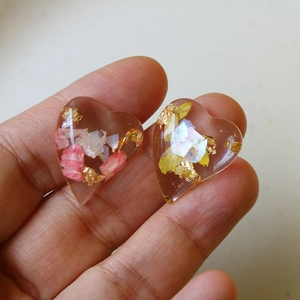 Macro view of handmade heart resin pendants with dried flowers and gold foil accents