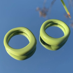 Dettaglio di anelli in resina verde matcha irregolari con finitura lucida su specchio