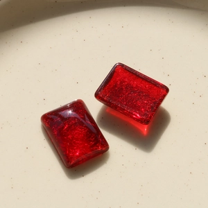 Macro detail of red translucent resin rectangle charms with fine golden glitter shimmer