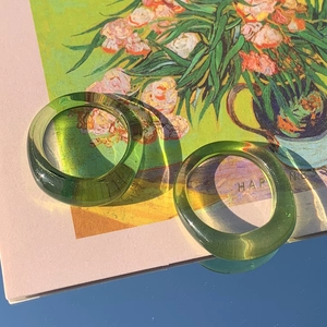 Set di anelli in resina verde minimalista con finitura traslucida su superficie a specchio