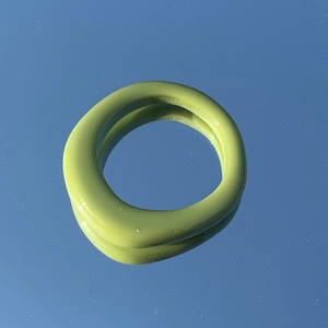 Dettaglio dell'anello irregolare in resina verde matcha su superficie riflettente blu