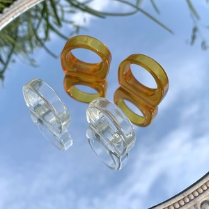 Primer plano de anillos de resina ámbar y transparente reflejados en un espejo circular