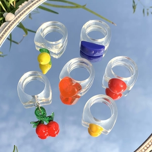 Primer plano de anillos coloridos de resina acrílica con dijes reflejando el cielo azul