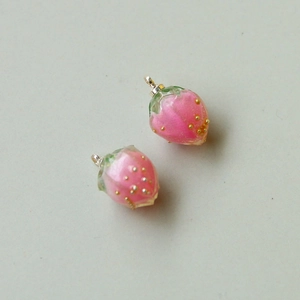 Detail von rosa Erdbeer-Anhängern aus Harz mit Goldperlen und grünen Blättern für DIY