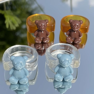 Primer plano de anillos de resina con ositos 3D en ámbar y azul con reflejos de espejo