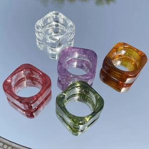 Transparent resin square rings set in five colors on a reflective mirror background