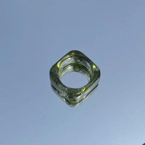 Macro shot of minimalist square resin ring in transparent ink green on reflective surface