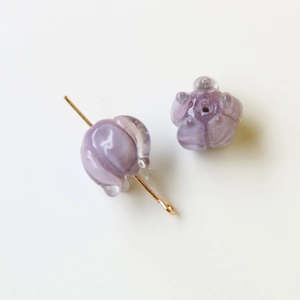 Vista macro de cuentas de vidrio violetas con forma de lirio y flores para joyería DIY