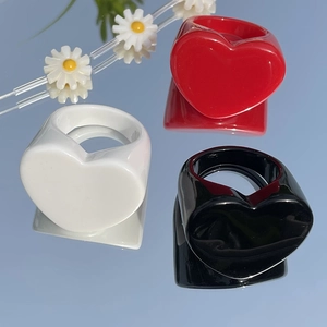 Polished heart-shaped resin rings in red, white, and black on a reflective mirror surface
