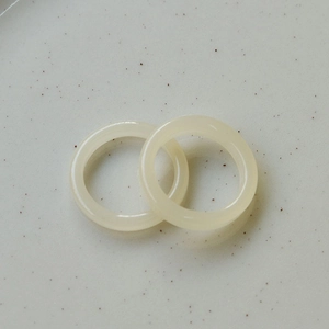 Macro detail of two minimalist milky white resin rings with a smooth polished finish