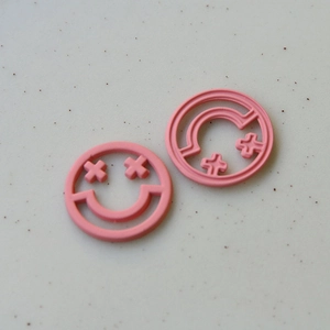 Dettaglio di accessori fai-da-te tondi rosa con faccina sorridente e motivi geometrici