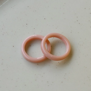 Close-up of minimalist light pink resin rings with smooth translucent finish on ceramic surface
