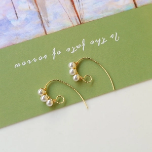Boucles d'oreilles élégantes en fil d'or torsadé avec perles blanches sur fond vert