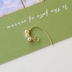 Boucles d'oreilles dorées tressées avec trois perles verticales sur carte verte