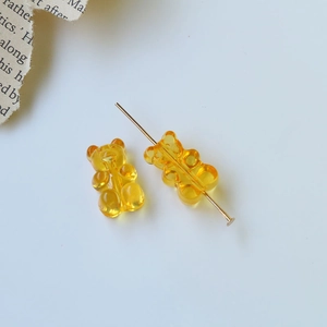 Dettaglio macro di perline a forma di orsetto in resina gialla con perni in metallo oro