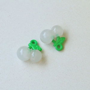 Gedetailleerd beeld van twee witte 3D kersenhangers met groene bladeren voor sieraden