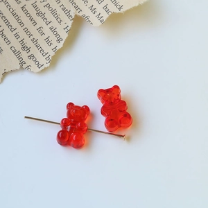 Detailed macro view of transparent red acrylic bear beads with gold flat head pins