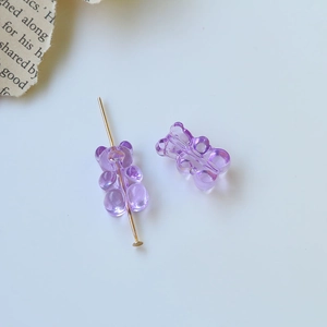 Dettaglio di ciondoli a forma di orso in resina viola traslucida con perno dorato
