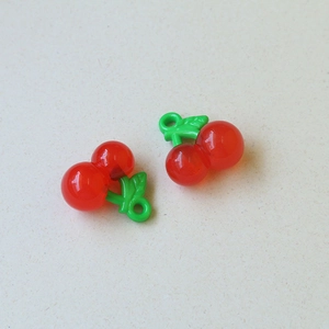 Macro detail van rode acryl kersenhangers met groene bladeren voor DIY sieraden maken
