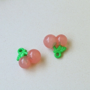 Detail van doorschijnende roze kersenhangers met groene bladeren voor DIY-sieraden
