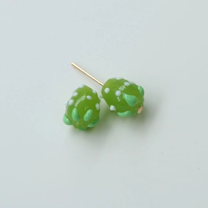 Close-up of handmade green succulent-style glass stud earrings with white dot details