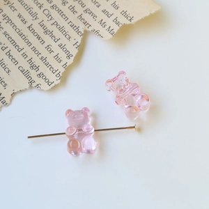 Detailed macro view of pink translucent resin gummy bears on golden jewelry pins