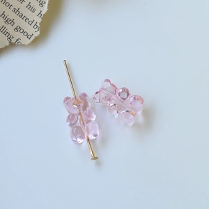 Dettaglio macro di perline a orsetto rosa con spillo dorato per gioielli DIY