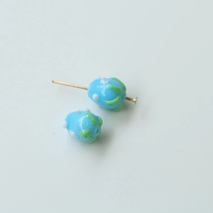 Macro view of light blue glass beads with green stripes and white dots for DIY jewelry