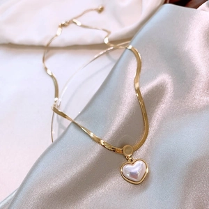 Elegant vintage pearl heart pendant on a gold snake chain with silk background